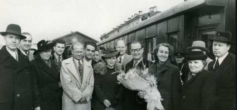 A group of people standing next to a train

Description automatically generated